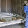 Operator using a sandblast lance in sandblasting cabinet 